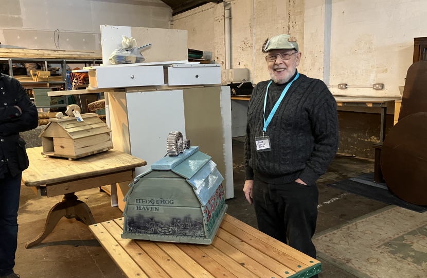 Member of Bexhill Men's Shed next to hedgehog house he built